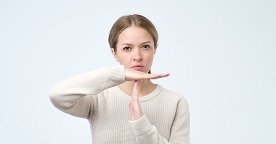 Young woman showing time out gesture with hands isolated on gray wall background. Negative human emotion (Demo)